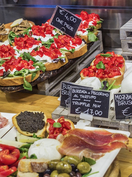 Bruschetta and antipasti display at a Florence food market, featuring local Italian ingredients.