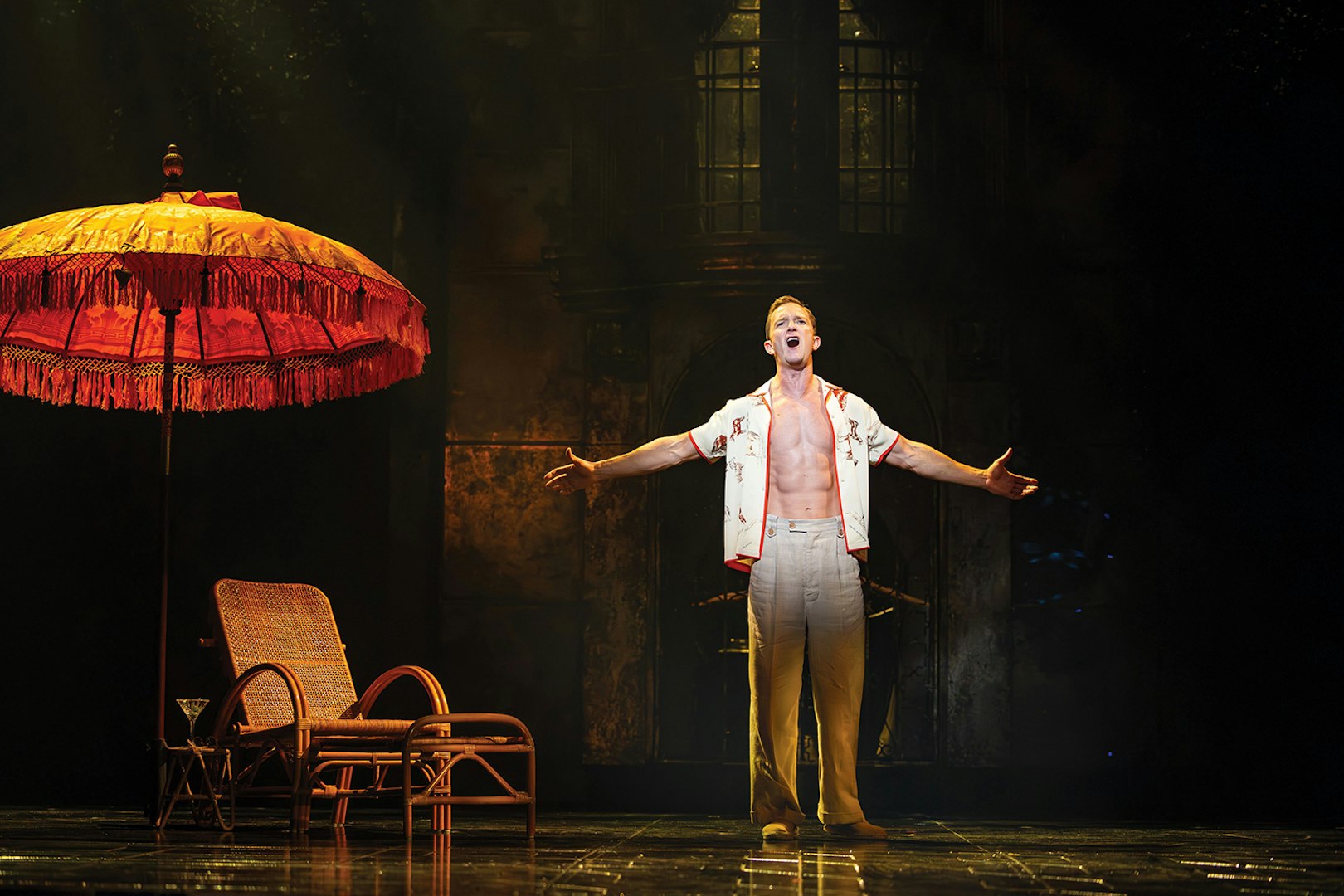 Performer singing under a large umbrella on stage, Sunset Boulevard.