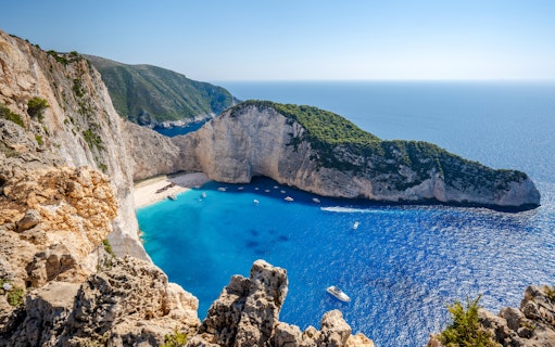 Navagio Beach and cliffs with boats in Zakynthos, Greece, viewed from above.