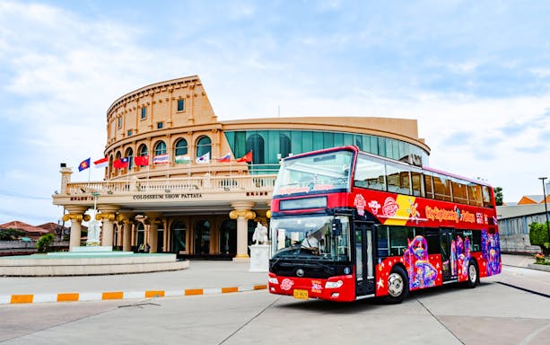 Red double-decker bus in front of Colosseum Show Pattaya on a hop-on hop-off tour.