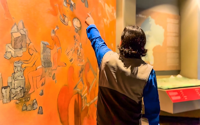 Visitor pointing at mural in the National Museum of Anthropology, Mexico City.