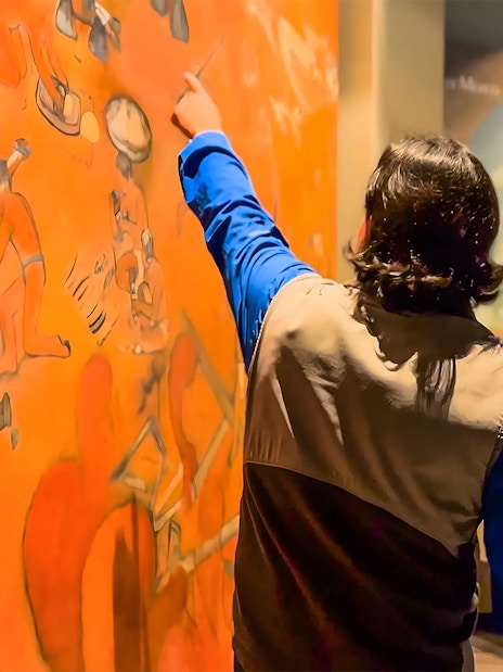 Visitor pointing at mural in the National Museum of Anthropology, Mexico City.