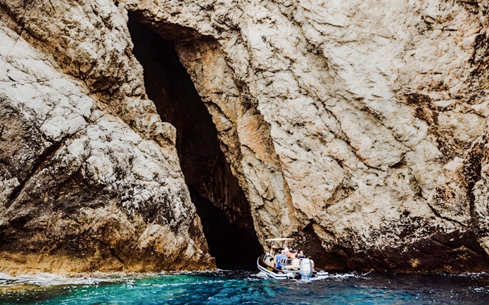 Boat entering Monk Seal Cave on Blue Cave, Blue Lagoon & 5 Islands tour.
