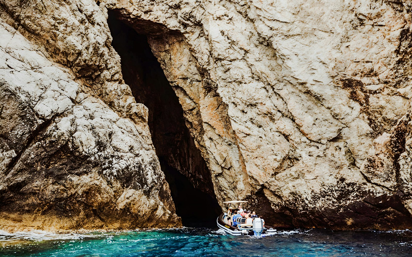 Boat entering Monk Seal Cave on Blue Cave, Blue Lagoon & 5 Islands tour.