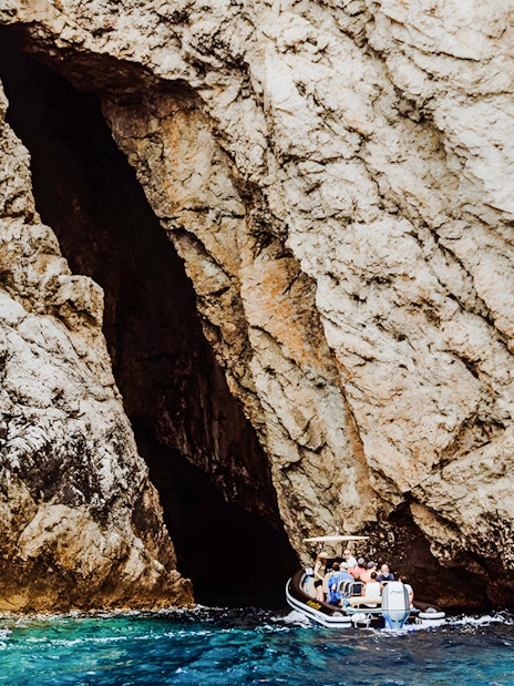 Boat entering Monk Seal Cave on Blue Cave, Blue Lagoon & 5 Islands tour.