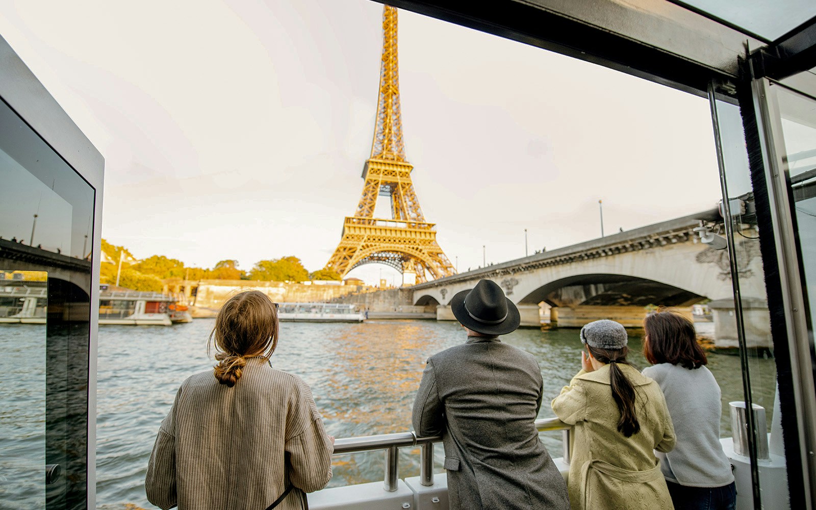 Tourists on Big Bus Paris tour with Eiffel Tower view, Seine River cruise in background.