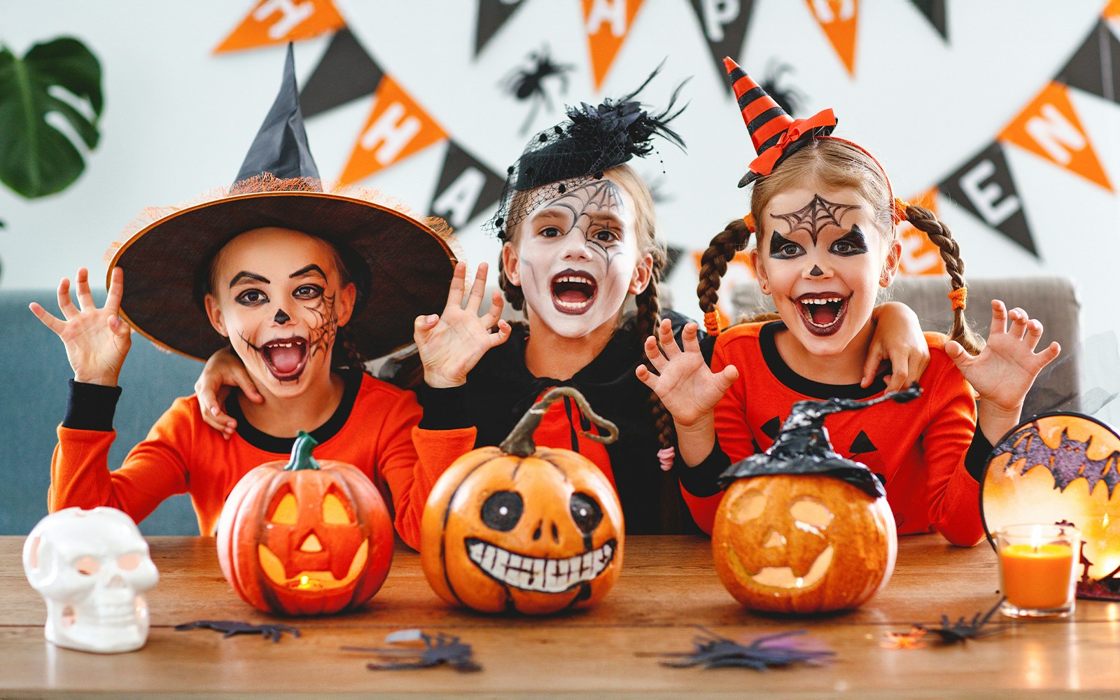 Children in Halloween costumes with carved pumpkins on a table.