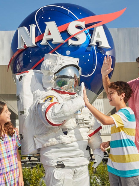 Family with astronaut at Kennedy Space Center, NASA globe in background.