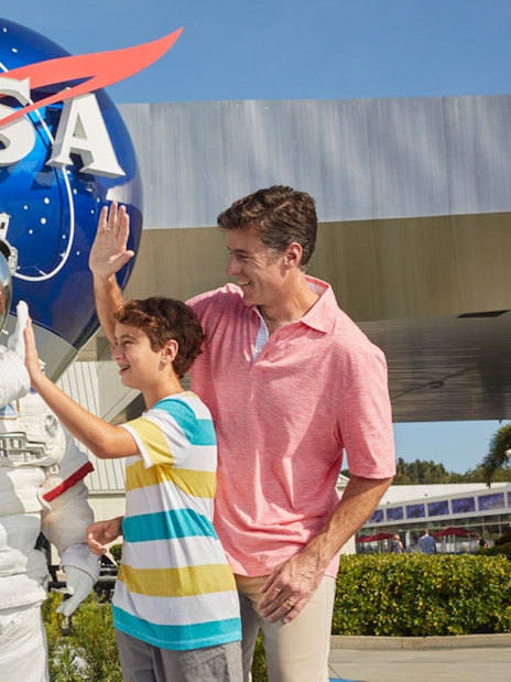 Family with astronaut at Kennedy Space Center, NASA globe in background.