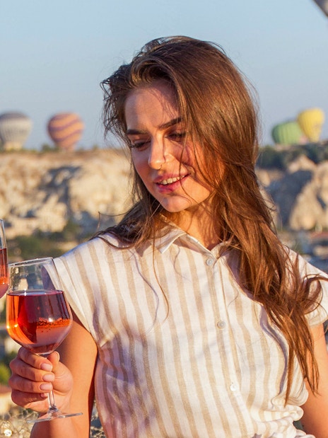 Friends toasting champagne on a jeep safari in Cappadocia with hot air balloons in the background.