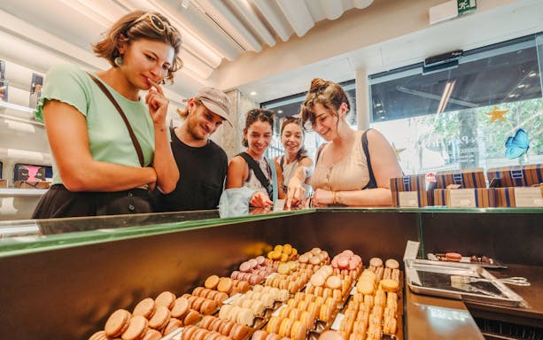 Group of people selecting macarons at a Parisian patisserie on the Ultimate Paris Food Tour.