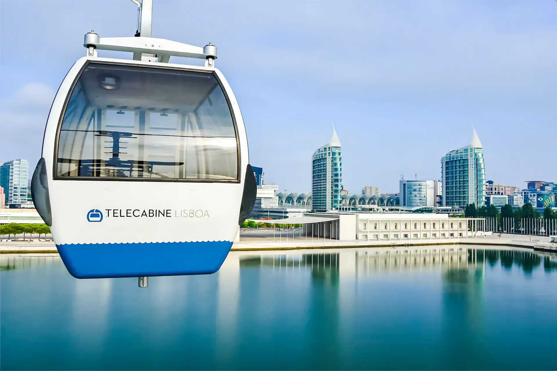 Lisbon cable car over water with cityscape in the background.