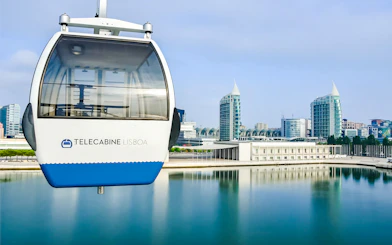 Lisbon cable car over water with cityscape in the background.