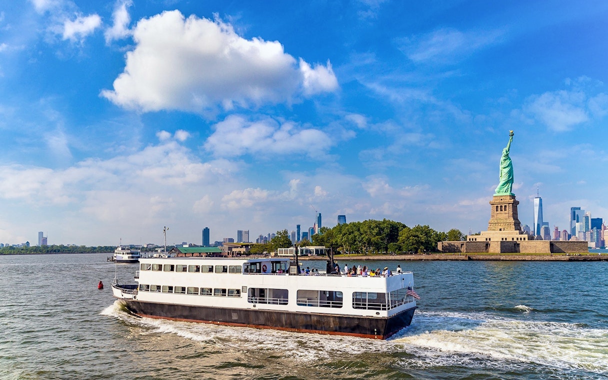 Ferry approaching Statue of Liberty with New York City skyline in background.