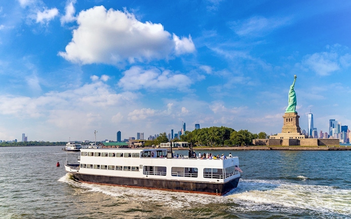 Ferry approaching Statue of Liberty with New York City skyline in background.