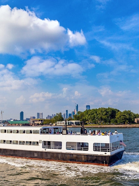 Ferry approaching Statue of Liberty with New York City skyline in background.