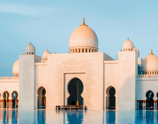 Grand Bur Dubai Masjid with domes and arches reflecting in water, Dubai.
