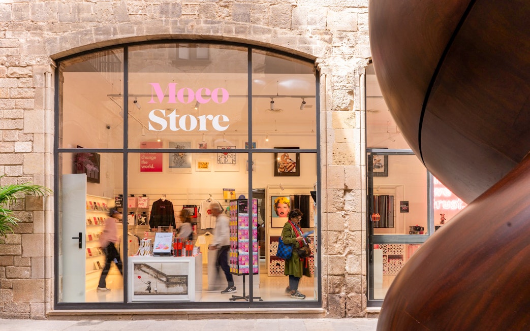 Moco Museum merchandise store entrance in Barcelona with art displays and visitors.