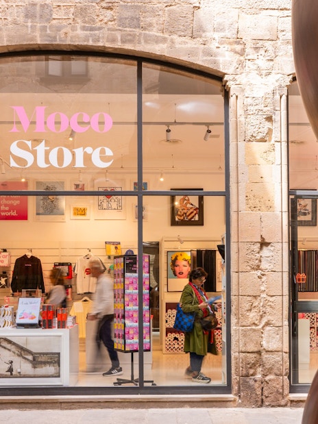 Moco Museum merchandise store entrance in Barcelona with art displays and visitors.