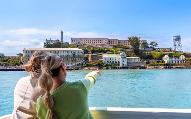 Ferry approaching Alcatraz Island from San Francisco’s Pier 33, with visitors pointing at the historic prison.