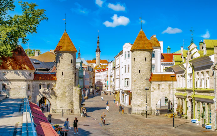 Viru Gate towers in Tallinn Old Town with cobblestone street and historic buildings.