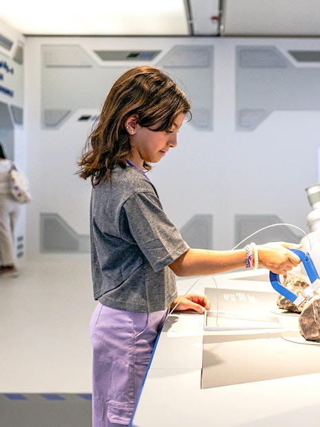 Young visitor exploring exhibit at Louvre Abu Dhabi.