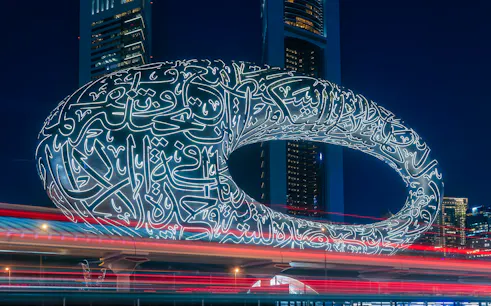Museum of the Future illuminated at night in Dubai with Arabic calligraphy.