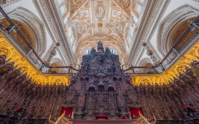 Córdoba Cathedral-Mosque interior with ornate wooden choir stalls and intricate ceiling.