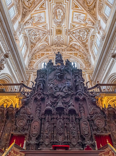 Córdoba Cathedral-Mosque interior with ornate wooden choir stalls and intricate ceiling.