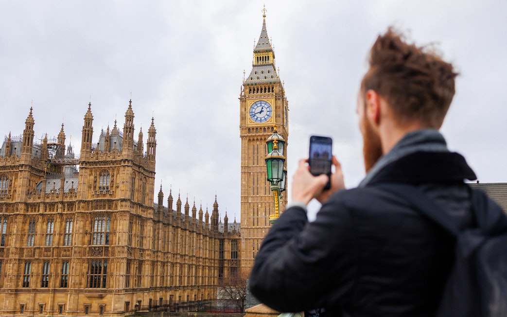 Visitor photographing Big Ben and Houses of Parliament, London.