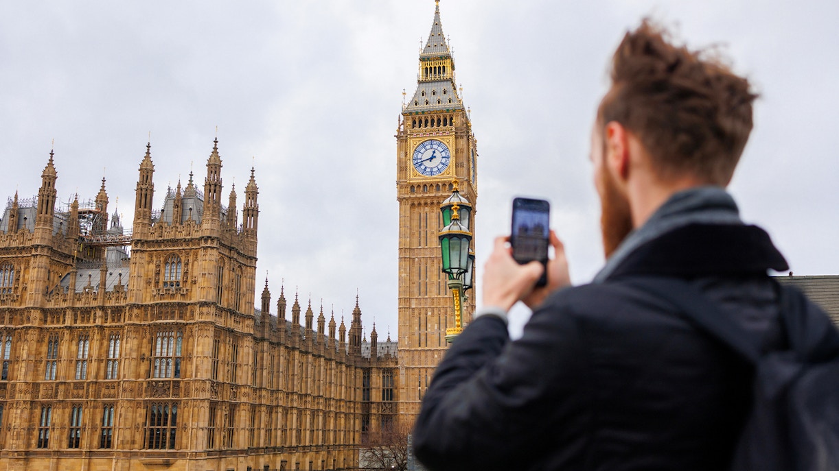 Visitor photographing the iconic Houses of Parliament in London during a guided tour.