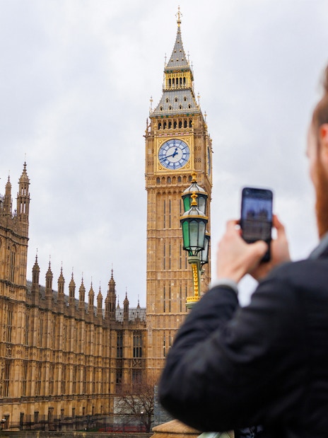 Visitor photographing Big Ben and Houses of Parliament, London.