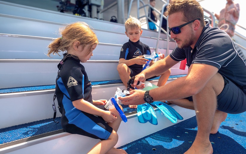 Children preparing snorkeling gear on Outer Great Barrier Reef trip from Cairns.