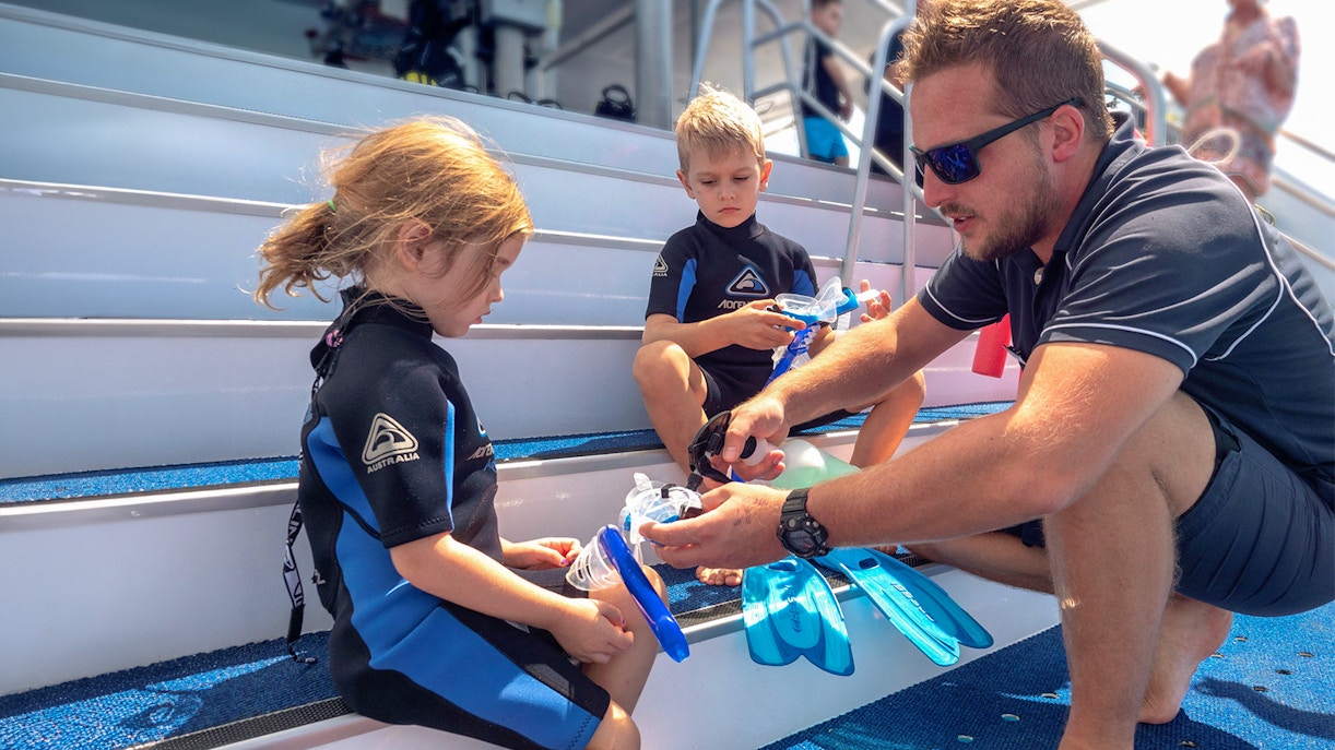 Children preparing snorkeling gear on Outer Great Barrier Reef trip from Cairns.