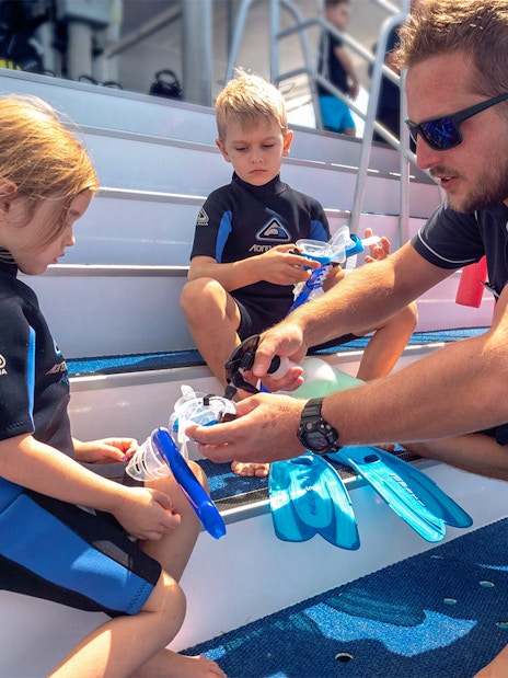 Children preparing snorkeling gear on Outer Great Barrier Reef trip from Cairns.