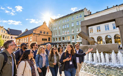 Tour group exploring Oslo with guide near fountain and historic buildings.