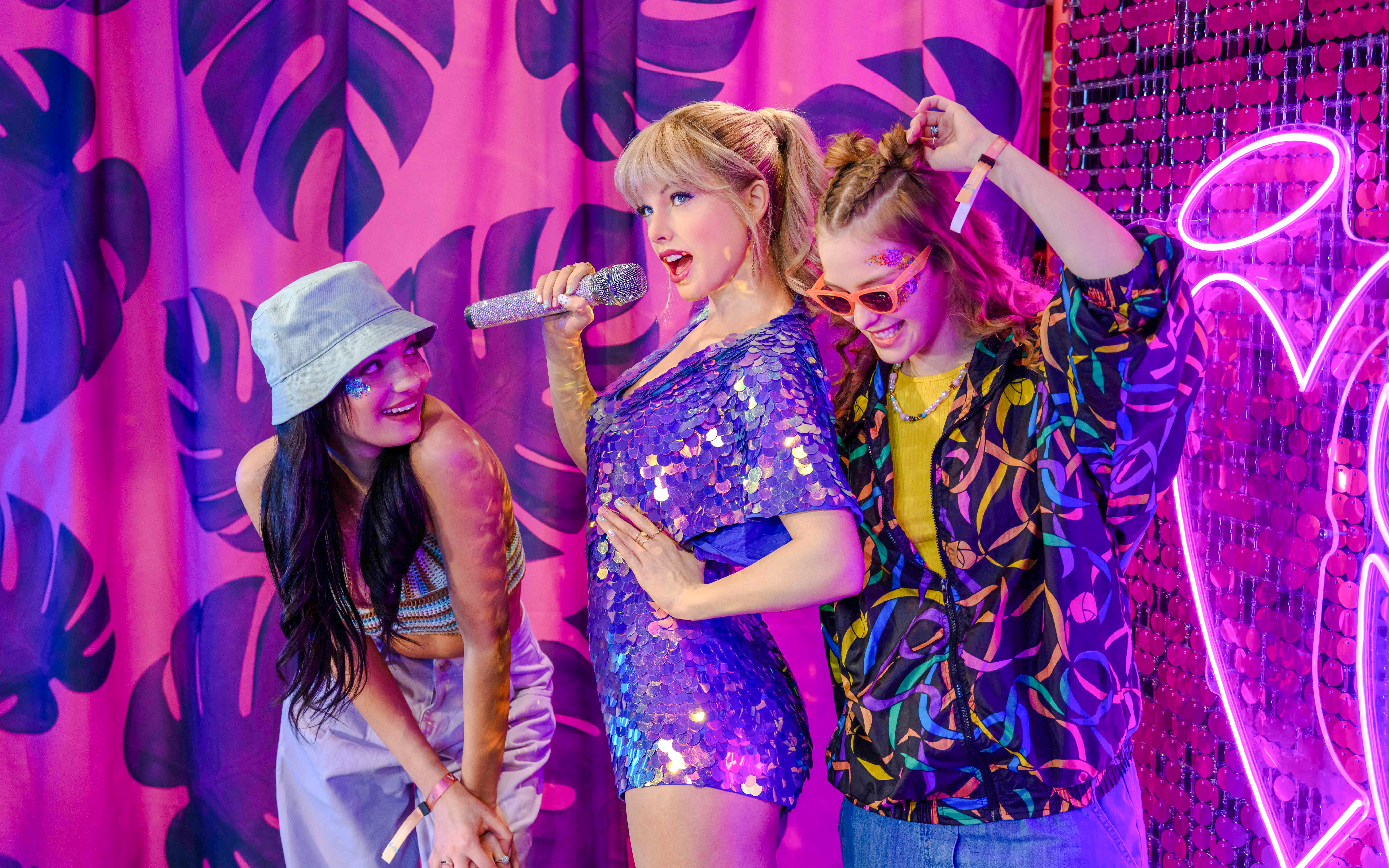 Madame Tussauds London wax figure of Taylor Swift with fans in colorful setting.