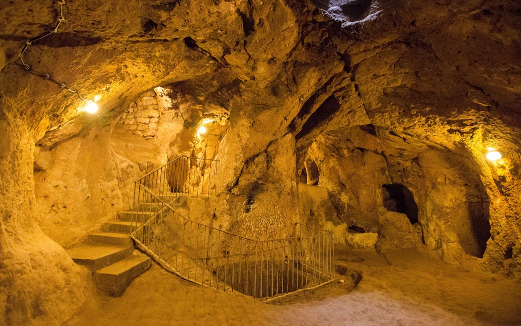 Cappadocia's Kaymakli Underground City with stone stairs and illuminated tunnels.