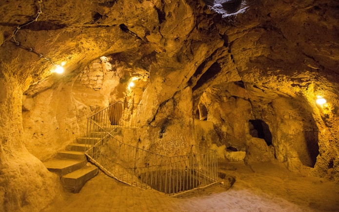 Cappadocia's Kaymakli Underground City with stone stairs and illuminated tunnels.