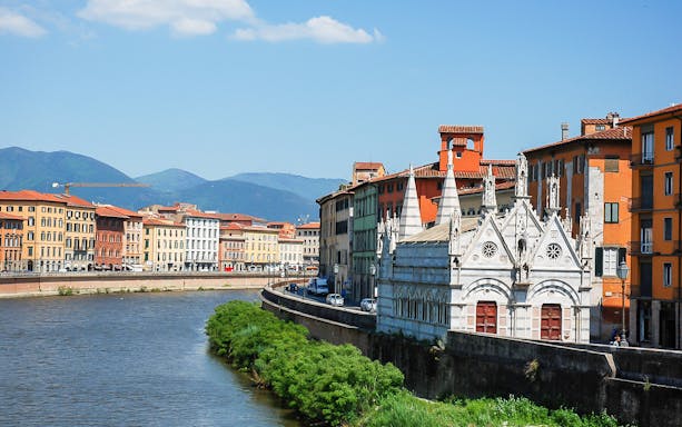 Riverside view of Pisa with Santa Maria della Spina church and colorful buildings.