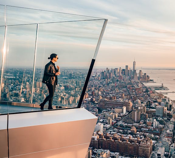 Women standing on Edge NYC observation deck overlooking Manhattan skyline.