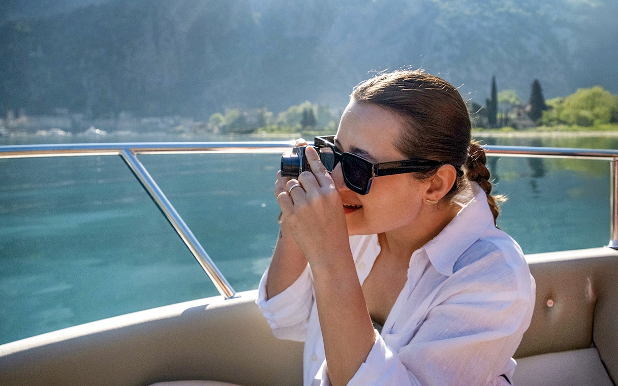 Guest taking photos on catamaran during Blue Cave cruise tour.