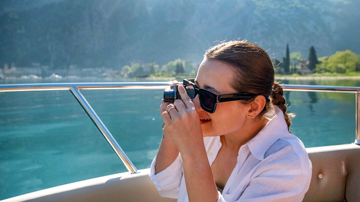 Guest taking photos on catamaran during Blue Cave cruise tour.