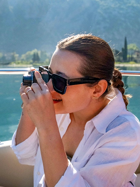 Guest taking photos on catamaran during Blue Cave cruise tour.