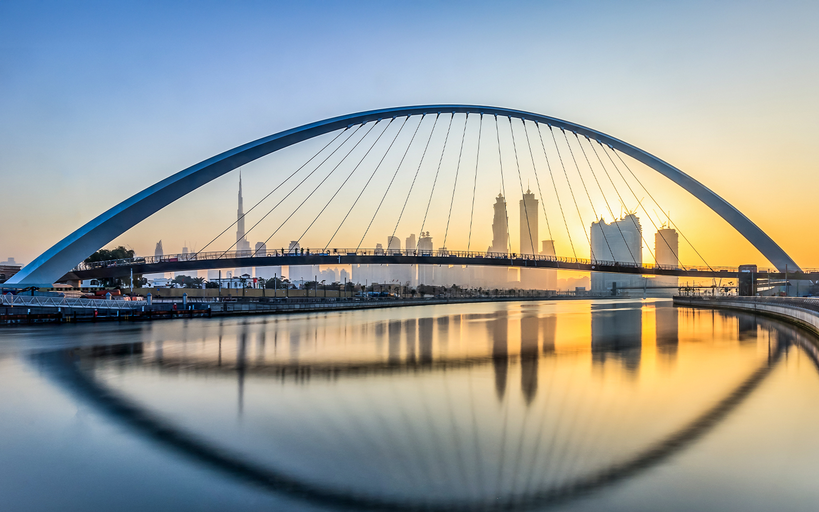 Dubai Water Canal at sunset with city skyline in the background.