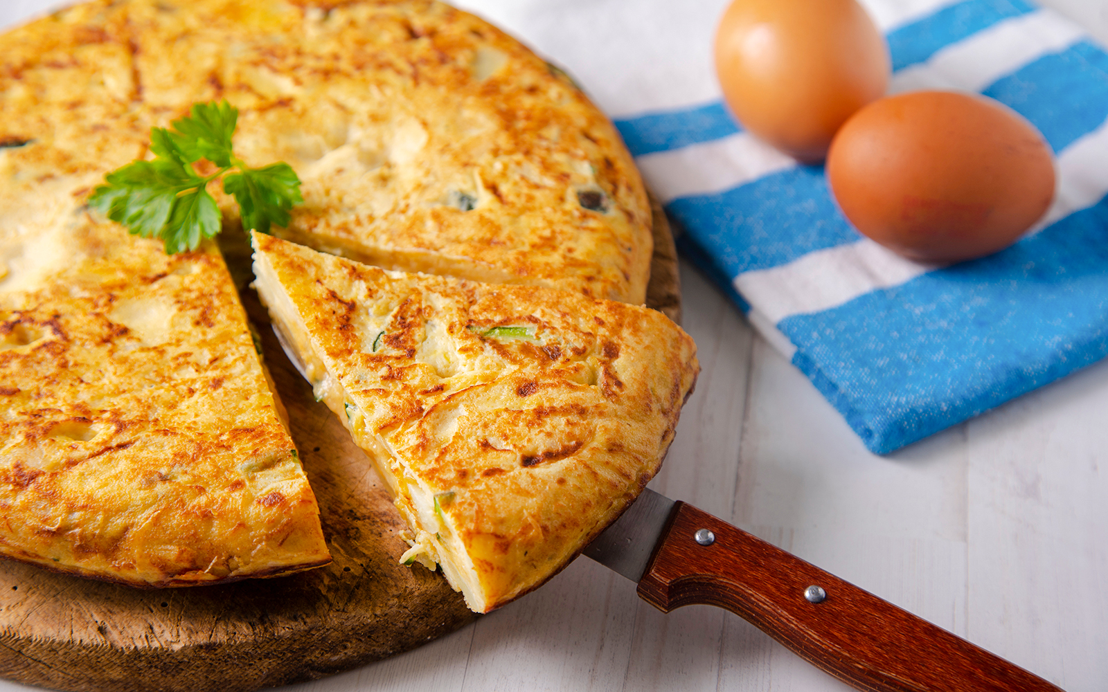 Mushroom omelette with potatoes and zucchini on a wooden board.