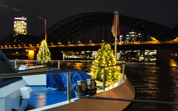 Boat with Christmas lights on the Rhine River, Cologne, near Hohenzollern Bridge at night.