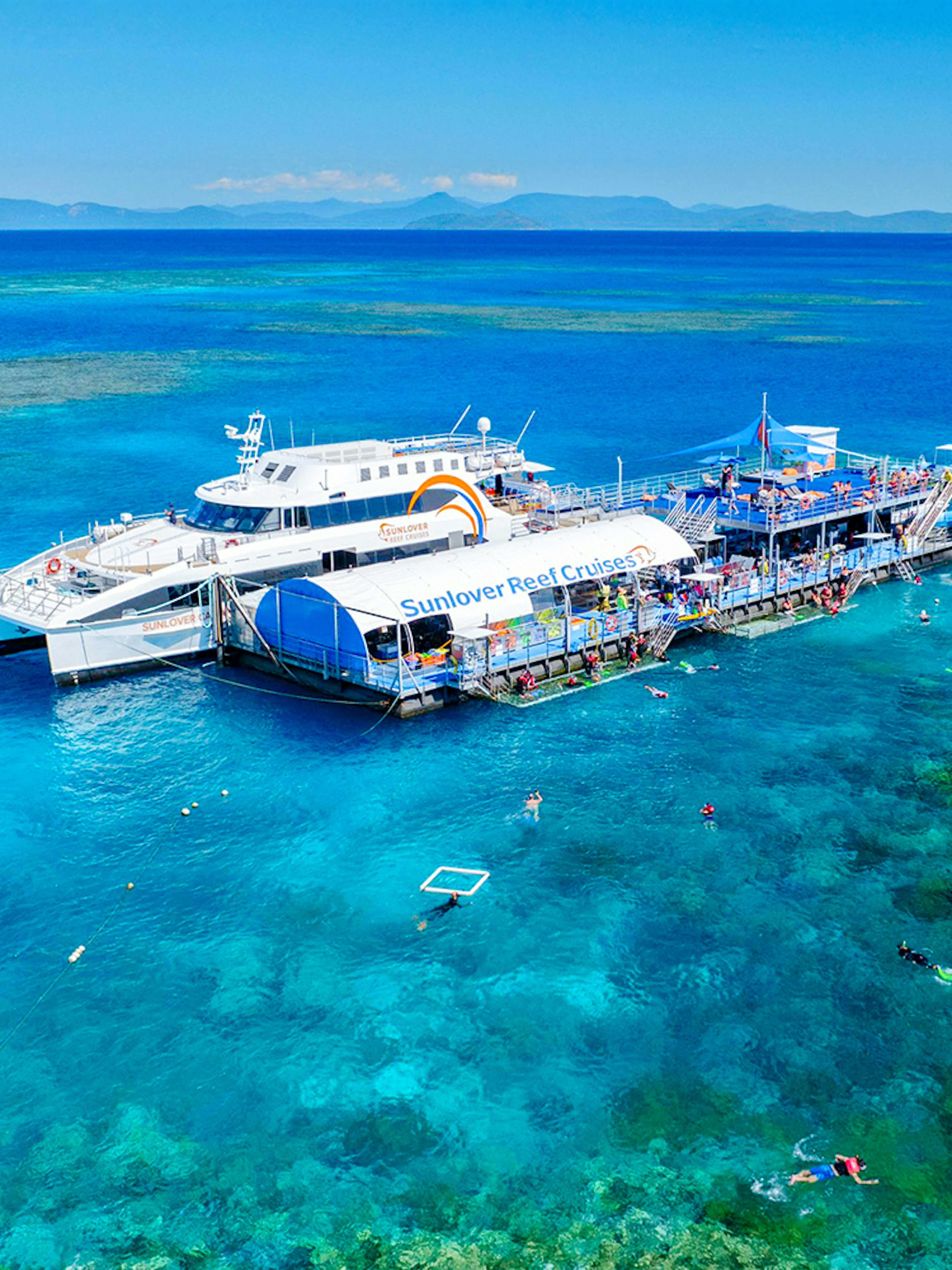 Cruise ship and pontoon near Moore Reef, Great Barrier Reef, Australia, with snorkelers in clear water.