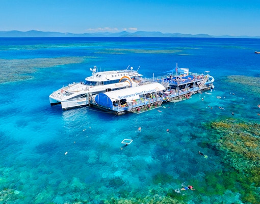 Cruise ship and pontoon near Moore Reef, Great Barrier Reef, Australia, with snorkelers in clear water.