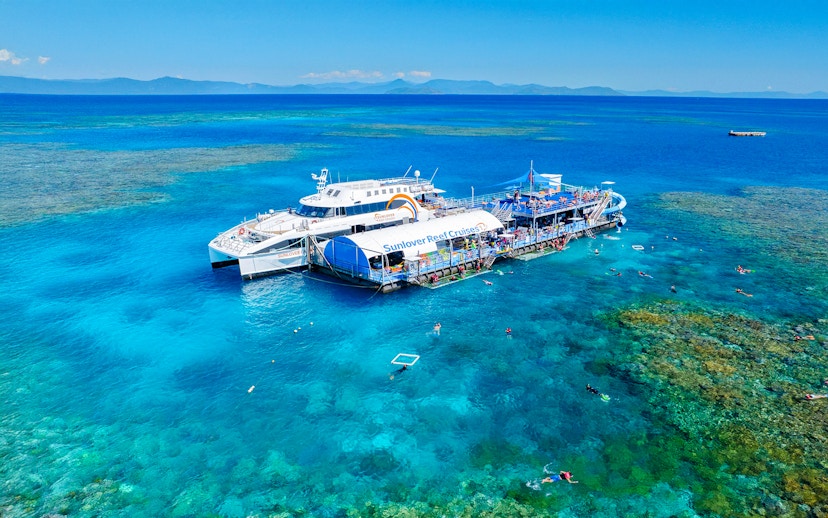 Cruise ship and pontoon near Moore Reef, Great Barrier Reef, Australia, with snorkelers in clear water.